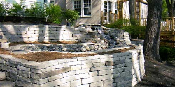 Terraced and curved stacked-stone retaining walls with water feature in Boulder